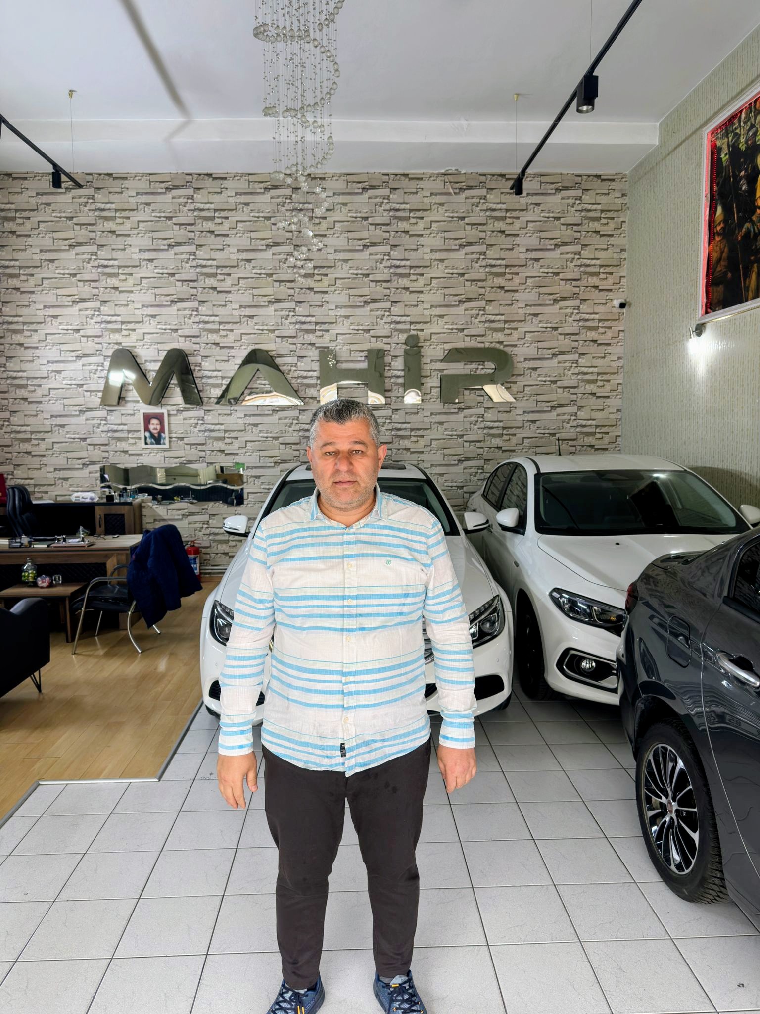 Mahir Ticaret galerisi önünde araçlar ve işletme temsilcisi